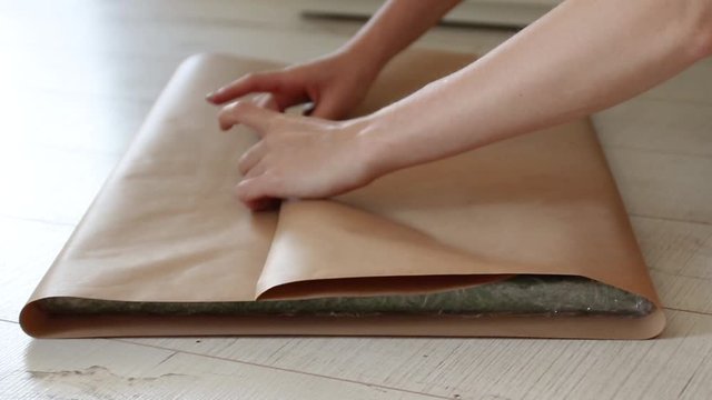 Female hands wrap a gift in craft gift paper. Preparation for a new year, birthday or christmas
