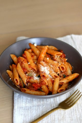 Plate of pasta with tomato sauce and eggplant, sprinkled with grated parmesan. Selective focus.