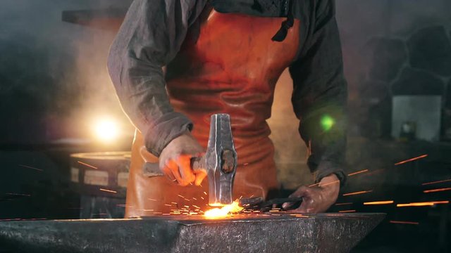 Forgeman is striking iron with a hammer in slow motion