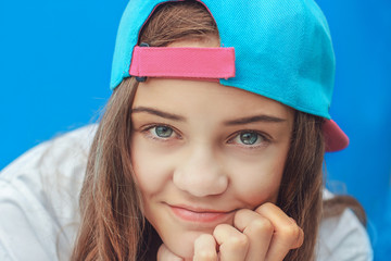 A beautiful girl in a baseball cap looks at the camera and smiles. Close-up portrait of a happy...
