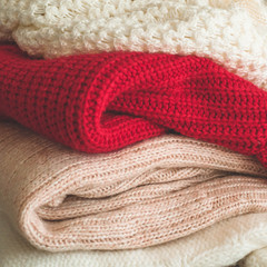 A stack of knitted sweaters in the interior of the living room. The concept of autumn winter comfort