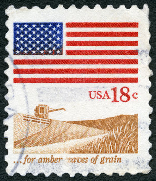 USA - 1981: shows an American Flag, Wheat Fields and harvester, for amber waves of grain