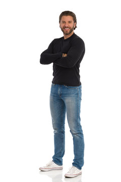 Smiling Man In Black Jersey, Jeans And Sneakers Is Standing With Arms Crossed