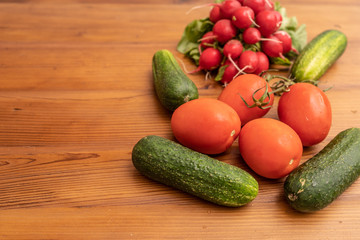 radishes tomato and cucumbers on wooden backround