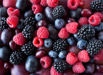 Ripe blackberries, blueberries, plums, pink grapes, raspberries. Mix berries and fruits. Top view. Background berries and fruits. Various fresh summer fruits. Black-blue and red food.