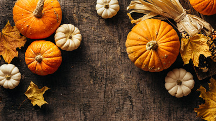Pumpkins and corn and autumn leaves on old shabby background. Autumn background with copy space. - obrazy, fototapety, plakaty