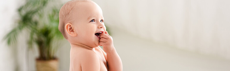 Panoramic shot of cute little child smiling and taking hand into mouth