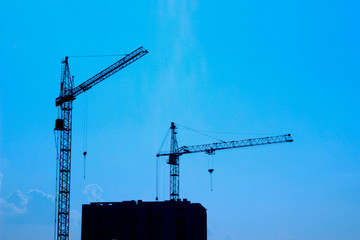 Blurred silhouette of a large construction crane .Construction site with two cranes.