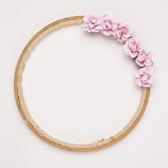 Obraz premium Pink roses decorated on circular wooden frame against white backdrop