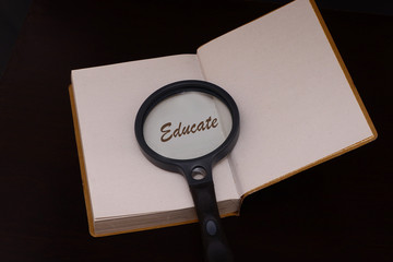 Magnifying glass with the word educate .