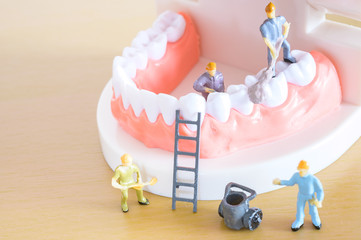 Miniature worker model cleaning teeth for dental clinic, good health care demonstrate how to clean, fix, taking care of teeth