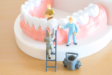 Miniature worker model cleaning teeth for dental clinic, good health care demonstrate how to clean,...