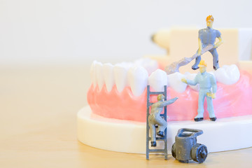 Miniature worker model cleaning teeth for dental clinic, good health care demonstrate how to clean, fix, taking care of teeth