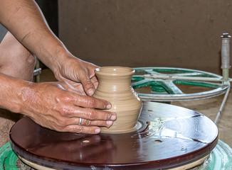 Making a jug of clay by hand on a potter's wheel. A gunner makes a jug of clay. A folk craft