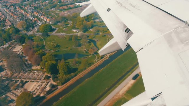 The plane is preparing for landing. Flying over water channels, greenhouses, farms with solar panels, houses, the route of the city of Amsterdam, Holland, the Netherlands