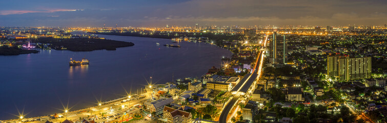 Fototapeta premium Panorama Street lights and lights from residential homes in the suburbs during sunset time, boat traffic Vehicle traffic in Samut Prakan, Thailand