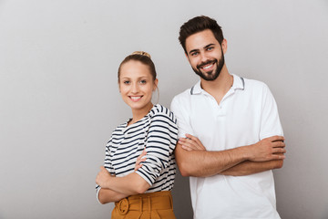 Smiling happy young loving couple friends man and woman posing indoors isolated over grey background.