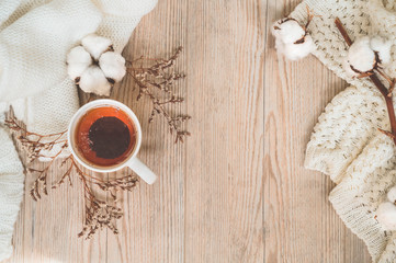 Background with warm sweaters and cup tea. Cozy still life in warm shades, space for text