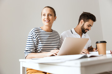 Loving couple friends man and woman sitting at the table indoors using laptop computer writing in...