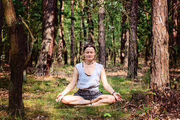 young woman meditating alone and silent in summer forest