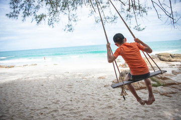 boy swinging in a swing on beach