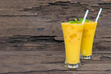 Mango smoothies yellow colorful fruit juice milkshake blend beverage healthy high protein the taste yummy In glass,drink to lose weight drink episode morning on a wooden background.