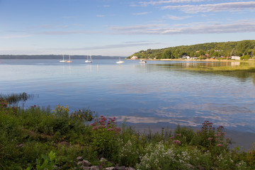 General view of the Cap-Rouge bay area with sailboats anchored in the St. Lawrence River and perennials growing on the waterfront during a golden hour late summer morning, Quebec City, Quebec, Canada
