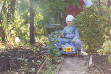 five-year-old boy smiling boy in a gray suit riding on a narrow path on a children's machine