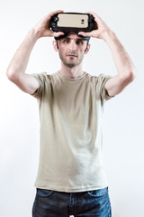 Portrait of a handsome brunet man with virtual reality goggles on head on white background
