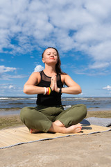 Fototapeta na wymiar A woman practices yoga by the sea or ocean. Healthy lifestyle and health care. Outdoor sports.