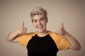 Portrait of handsome transgender teenager making thumbs up gesture feeling happy and successful
