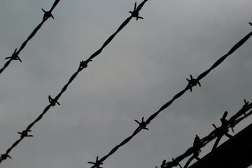 barbed wire on background of clouds