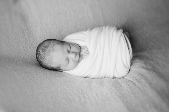 newborn baby sleeps wrapped in a blanket. concept of childhood, healthcare, IVF. Black and white photo