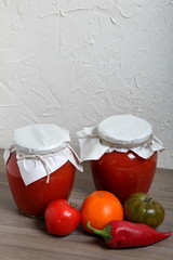 Homemade seasonal preparations. In glass jars, tomato paste. The neck of the cans is wrapped in paper and tied with rope. Nearby vegetables for cooking ketchup.