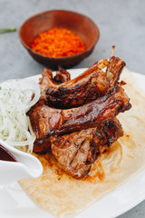 Pork ribs and tomato sauce on white plate. Close up view