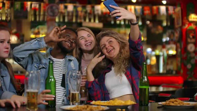 Group of diverse friends taking selfie on mobile phone in bar