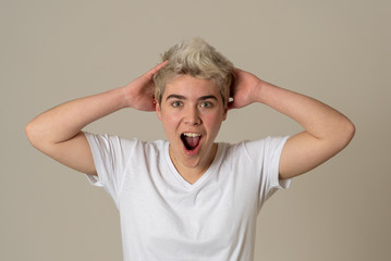 Happy young attractive teenager man shocked with surprised funny face. Human expressions