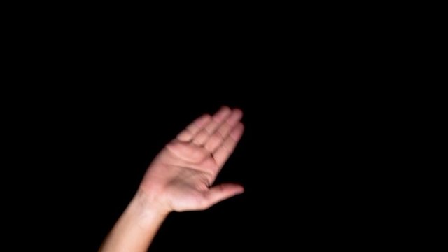 Hand waving bye bye gesture on a black chroma digital key screen, close up