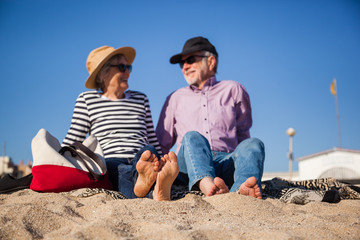 Elderly couple sitting on mediterranean beach, concept happy active seniors