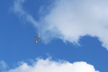 Fototapeta na wymiar Airplane flying in the sky on background of white clouds. Commercial plane during the turn, turbulence concept