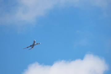 Airplane flying in the sky on background of white clouds. Commercial plane during the turn, turbulence concept