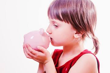 Happy cute little child girl smiling and holding pink piggy bank. Concept of teaching children business skills. Humorous photo.