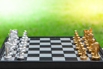 Chess game, set the board waiting to play in both gold and silver pieces on green grass background