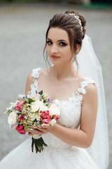 Naklejka premium Beautiful cheerful bride with a bouquet. Beautiful wedding bouquet in hands of the bride. Bride with elegant hairstyle and makeup