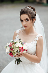 Naklejka premium Beautiful cheerful bride with a bouquet. Beautiful wedding bouquet in hands of the bride. Bride with elegant hairstyle and makeup