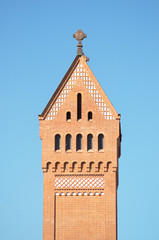 Church brick tower with a cross against the blue sky