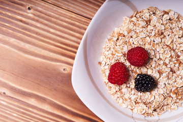 Cereal porridge with fresh berries on a wooden table