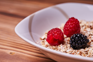 Cereal porridge with fresh berries on a wooden table