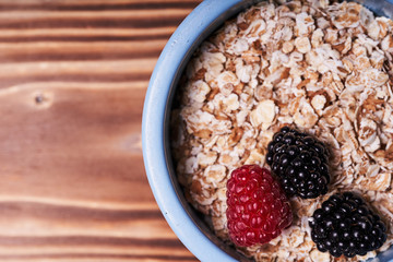 Blue pot of cereal with fresh berries on a wooden table