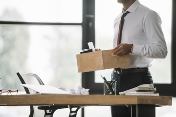 cropped view of dismissed businessman holding wooden box in modern office